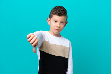Little kid boy isolated on blue background showing thumb down with negative expression