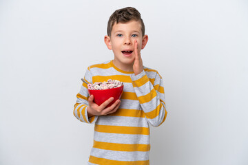 Little caucasian boy holding a cereal bowl isolated on white background with surprise and shocked...