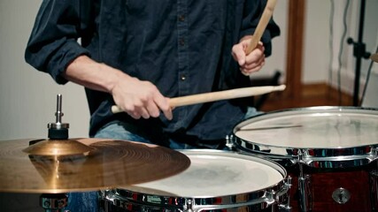 Close-up video of a drummer playing, focusing on hands and drumsticks. The angle captures dynamic motion and rhythm, emphasizing musical energy.