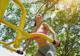A young woman are exercising on a machine in a park