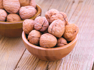 Walnuts filling a wooden bowl resting on a wooden table