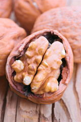 Walnut kernels resting in cracked shell on wooden surface