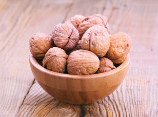 Walnuts filling a wooden bowl sitting on a wooden table