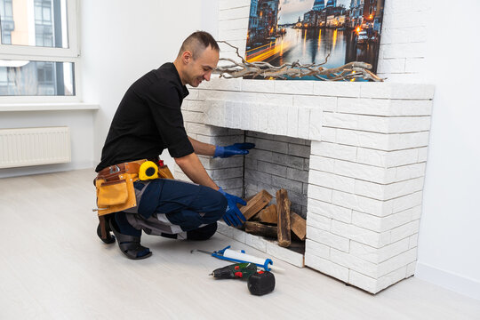 Worker building brick stove or fireplace checking it with spirit level