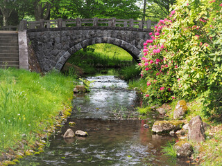 石造りの橋に流れる小川と鮮やかな自然植物の風景