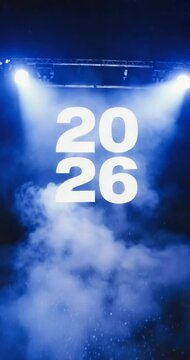Bold white &ldquo;2026&rdquo; text illuminated by blue spotlights and fog on stage, symbolizing new year, celebration, and future events