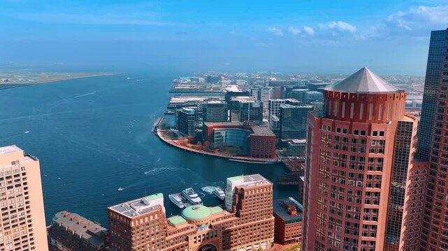 Stunning flight at the skyscrapers in the harbor of Boston. Spectacular scenery on the waterscape of the Charles River with boats on. Aerial view.