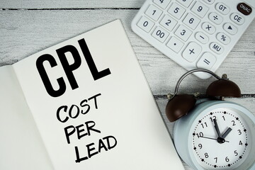 CPL Cost Per Lead text on paper notebook page with alarm clock and calculator on wooden background