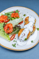 Savory cottage cheese pancakes (syrniki) served with sour cream and fresh herbs. Traditional Eastern European dish. Close-up, top view.


