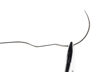 Close-up of a surgical needle threaded with non-absorbable suture. Sharp point and fine thread against a white background.