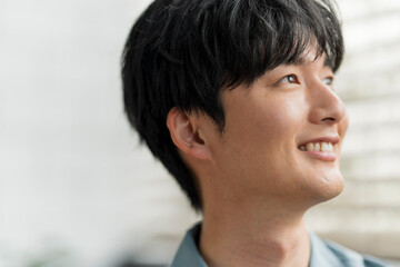 Obraz premium 微笑んでいる若い日本人男性の横顔。