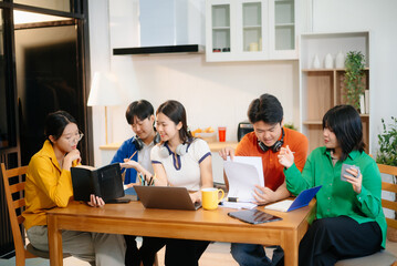 young team brainstorming ideas with laptops, coffee, and notes in a cozy indoor setting. Perfect for education, startup, teamwork, and collaboration themes.