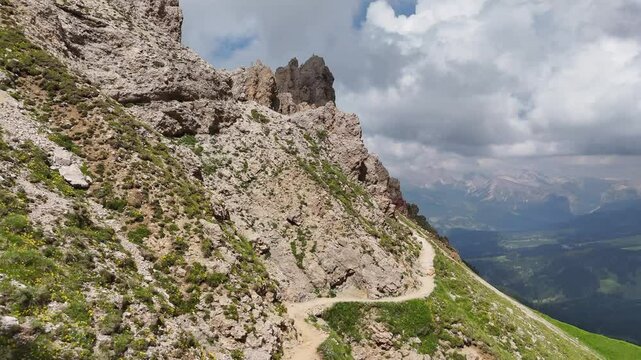 Forward drone flight above mountains and hiking trail near tierser Alpl, Rifugio Alpe di Tires towards Forcella Denti di Terrarossa. Mountain slope with trail, and view in the valley. Wonderful Dolomi