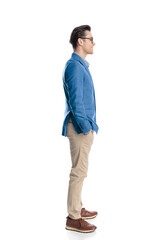 Fototapeta premium happy young guy with glasses holding hands in pockets while waiting in line