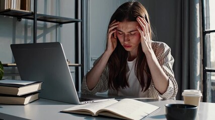 A stressed woman works on a laptop at a desk, captured in a medium shot. The video conveys a tense, focused atmosphere in a home office setting. - Powered by Adobe