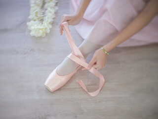 A womans hands tying ballet slippers. Pastel and white tones © wisannumkarng