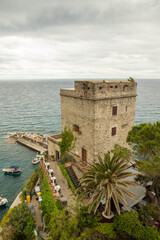 View of Monterosso beach with colorful umbrellas, historic villas, and green hills in Cinque Terre...
