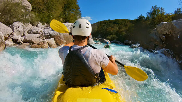 A thrilling kayaking adventure unfolds as a person navigates a yellow kayak through a rapid river, showcasing their skill and determination. A close-up shot captures the kayaker's white helmet and.