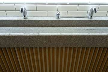 Automatic water faucet and soap dispenser and stone sink in a public toilet.