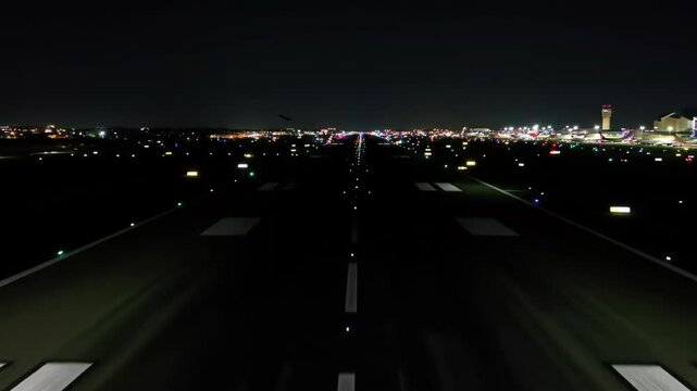 Night view of empty airport runway with illuminated lights and city