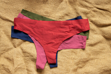 Women's seamless thong panties of different colors on a textile background, underwear