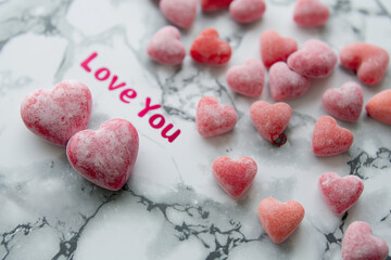 Obraz premium Heart-shaped candies and sweet message on a marble surface inspire feelings of love and affection for special moments. Generative AI