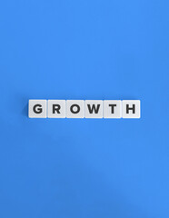 Close-up of Letter Tiles Spelling &lsquo;Growth&rsquo; on Blue Background.