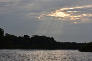 the sun's rays penetrate the clouds leaving a ray of light on the horizon above the Dnipro river