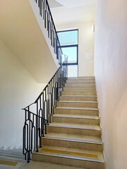 Detail of a flight of stairs with concrete steps and iron railings inside a building. Close-up, vertical photograph.
