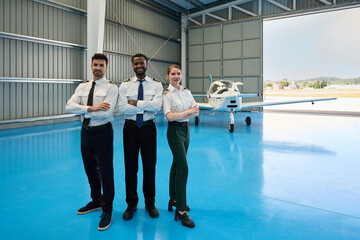 Confident student pilots posing with arms crossed in aircraft hangar © alvaro