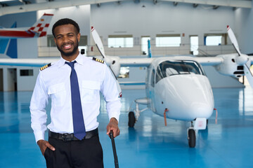 Smiling pilot posing with suitcase in aircraft hangar © alvaro