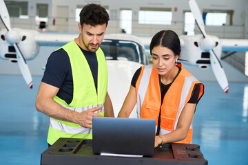 Aircraft mechanics using laptop for maintenance in hangar