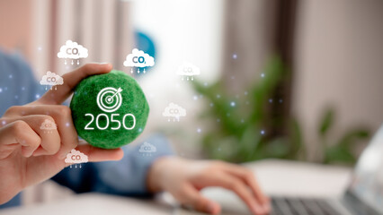 Sustainability and carbon neutrality goal for 2050, with hand holding green eco ball surrounded by CO2 icons, representing environmental commitment and climate action target.