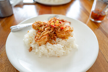 Stir Fried Shrimp and cooked rice topped  in white plate on wooden table at restaurant.Top view