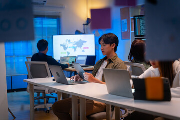 group of Happy young asian business people chatting happily after a night of overtime work in the office.Supervisor chats with employees after working together planning success strategy enjoy teamwork