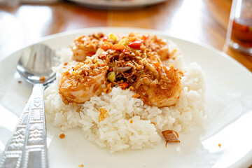 Stir Fried Shrimp and cooked rice topped  in white plate on wooden table at restaurant.Top view