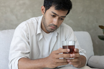 Depressed young man addicted feeling bad drinking whiskey alone at home, stressed frustrated lonely drinking alcohol suffers from problematic liquor, alcoholism, life and family problems