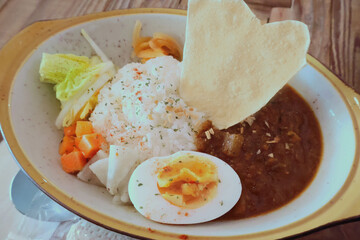 Indian-Japanese Fusion Curry Rice with Boiled Egg and Crispy Papad on Rustic Plate