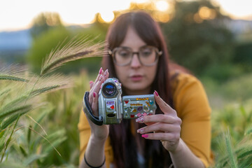 Videographer checking footage on a vintage camcorder at sunset in nature