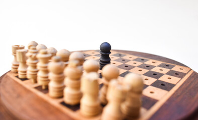 one black chess piece against all. concept of competition background. wooden chessboard.