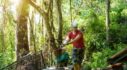 A man is walking across a challenging ropes course in the extreme park