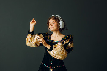 Portrait of a young aristocratic woman with headphones on her head and dressed in a medieval dress listens classical music