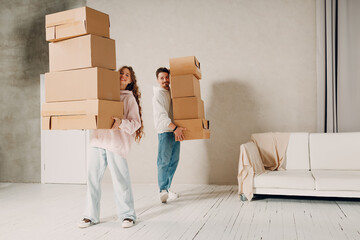 Happy young family couple man and woman moving with cardboard boxes to new estate home apartment.