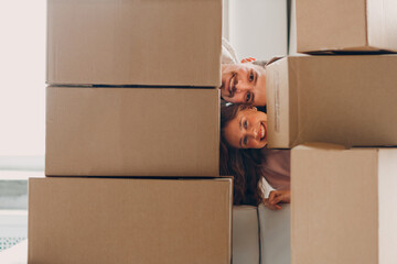 Happy young family couple man and woman portrait after moving cardboard boxes to new real estate apartment.