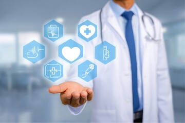 Doctor wearing white coat and stethoscope presenting medical icons in his hand