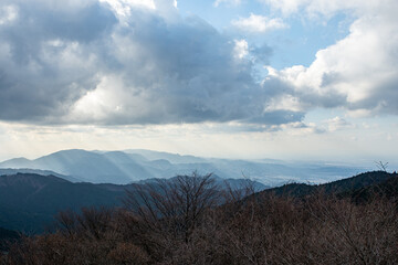 冬の金剛山ちはや園地展望台から見た、雲間から差し込む光芒が照らす広がる山々の風景
