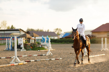Woman rider jockey in helmet and white uniform preparing horse racing