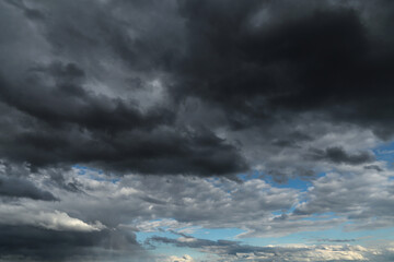 Epic Dramatic storm dark grey black cumulus rain clouds against blue sky background texture, thunderstorm