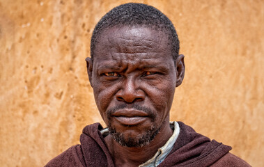 Fototapeta premium Portrait of a real elderly African man with deep wrinkles and expressive eyes. A natural and emotional image capturing human strength, wisdom, and timeless character.