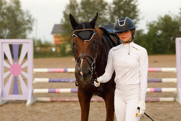 Jockey rider in uniform portrait holds bridle of dressage horse during equestrian jumping competition show